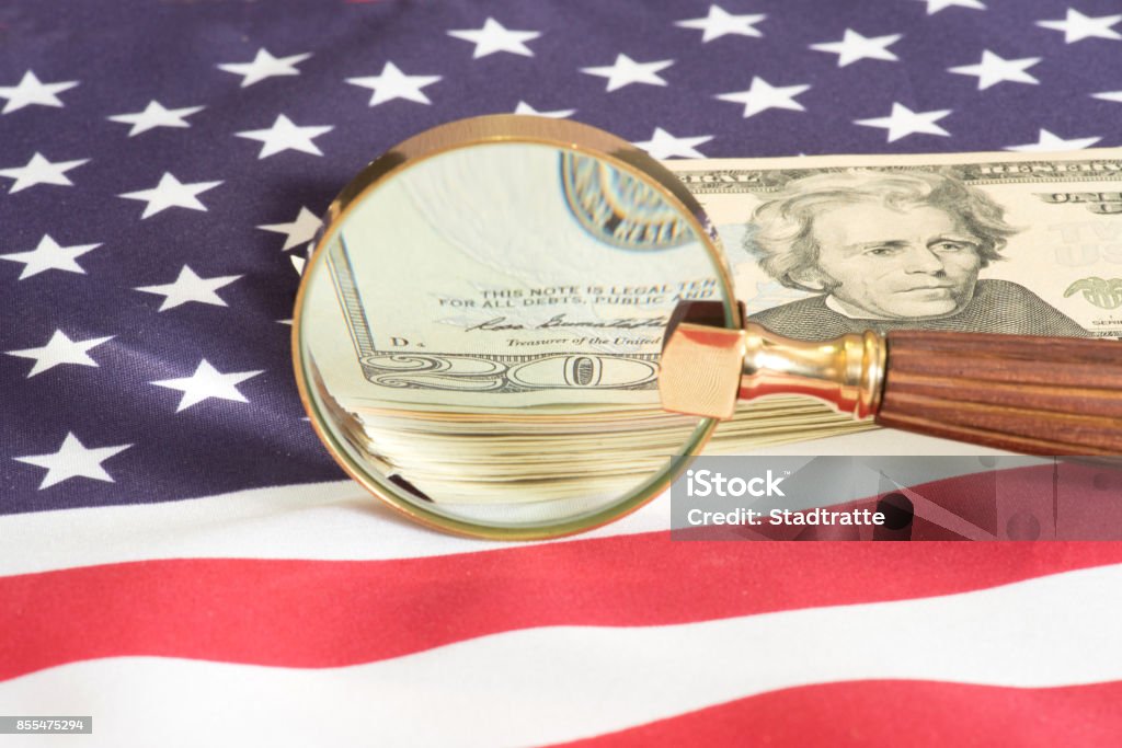 U.S. flag and dollar money under the microscope Flag of the USA and dollar money under the magnifying glass Tax Evasion Stock Photo