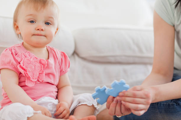 istock Woman showing a puzzle piece to her baby while sitting on a carpet 855475430