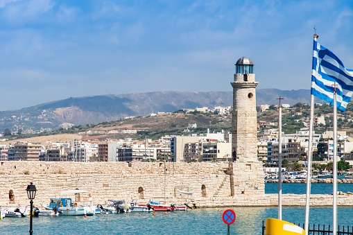 Lighthouse in the Venetian harbor of Rethymno and a flag of Greece