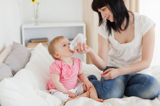 istock Charming brunette female bottlefeeding her baby on a bed 855483964
