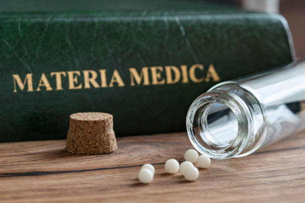 um frasco de glóbulos homeopáticos com um materia medica homeopático - homeopatic medicine - fotografias e filmes do acervo