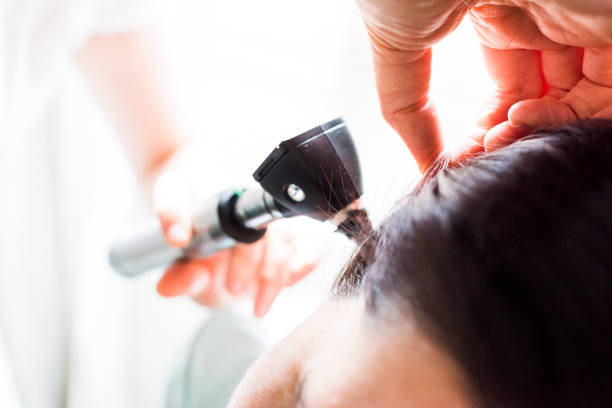 istock Woman examining patient with otoscope 855484738