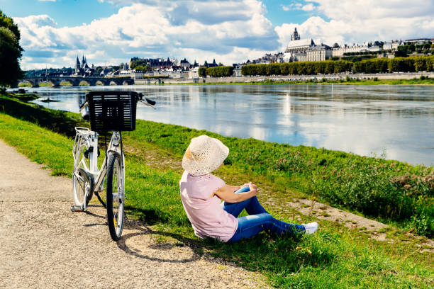 Senior woman cycling Loire Valley, France Senior woman cycling along the path beside the Loire River at Blois in the Loire Valley region of France. loire valley photos stock pictures, royalty-free photos & images