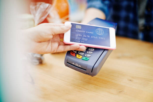 istock Customer placing smart phone over credit card reader in delicatessen 855489152