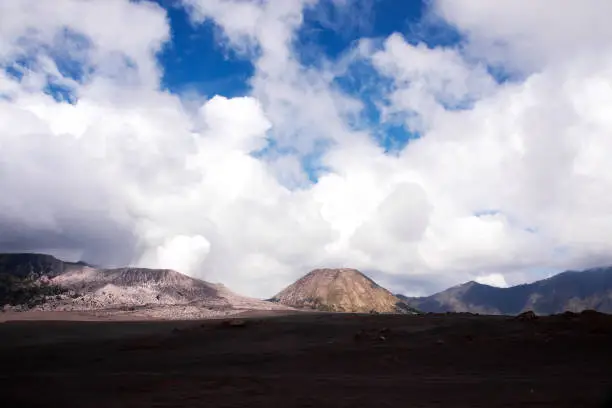 Mount Batok sitting next to the active volcano mount Bromo, with blue skies and white clouds at the Tengger Semeru National Park in East Java, Indonesia.