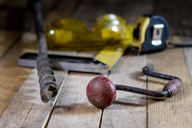 Hands holding a drill and screwdriver on a white background