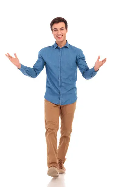 smiling casual man welcoming you and walking forward on white studio background