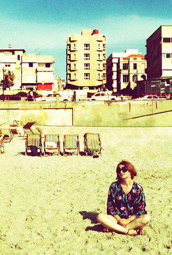 Vintage image of a woman sitting on the sand at the beach of tel Aviv in the seventies