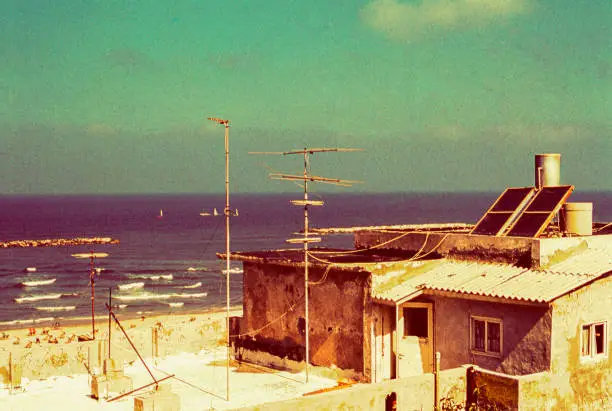 Vintage image of an old building at the beach of Tel Aviv with solar water heater and tv antennas.
