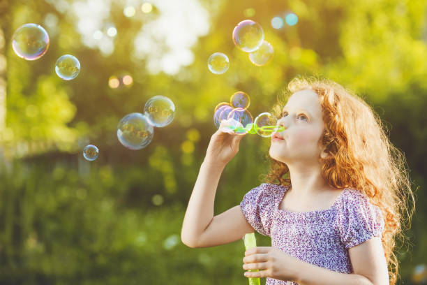 istock Little girl blowing soap bubbles in summer park. 855497450