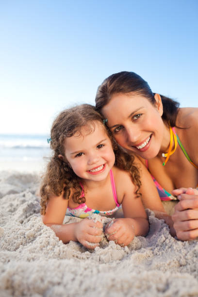 istock Mother and daughter lying down on the beach 855497972