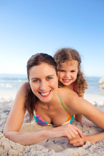 istock Mother and daughter lying down on the beach 855497992