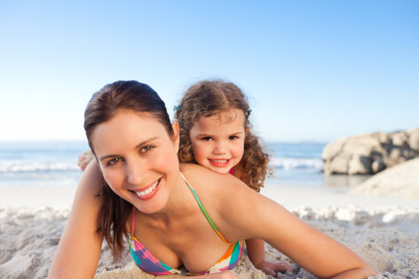 istock Mother and daughter lying down on the beach 855497996