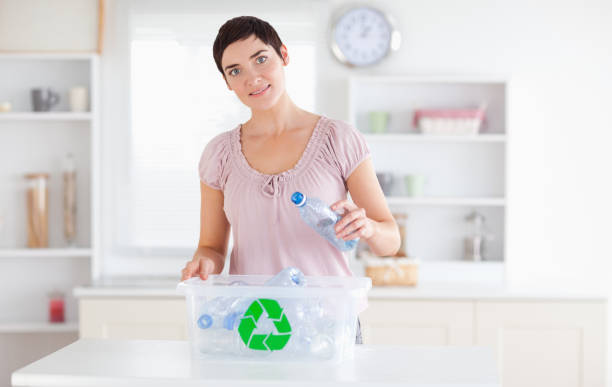 istock Cute Woman putting bottles in a recycling box 855498084