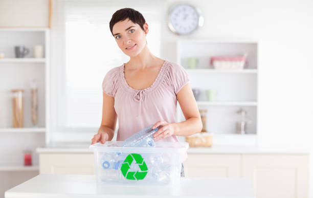 istock Smiling Woman putting bottles in a recycling box 855498126
