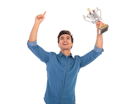 excited young casual man with hands in the air celebrating success and winning first place and award on white background