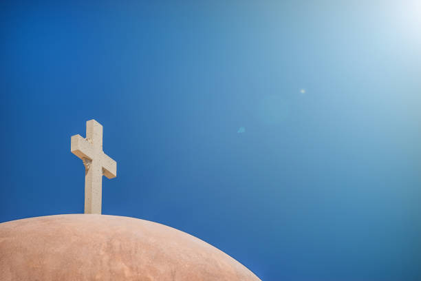 istock White Christian cross in front of a cloudy sky with copyspace 855504154