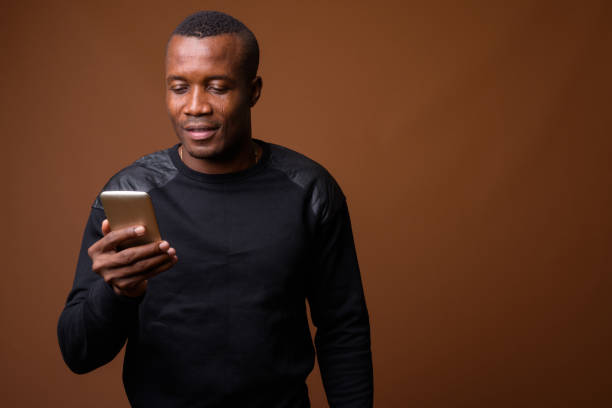 istock Studio shot of muscular African man using mobile phone against colored background 855505102