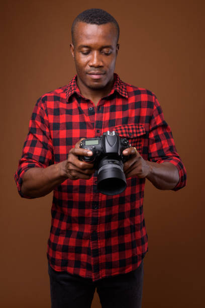 istock Studio shot of muscular African man with camera against colored background 855505452