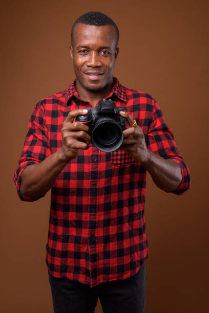 istock Studio shot of muscular African man with camera against colored background 855505462
