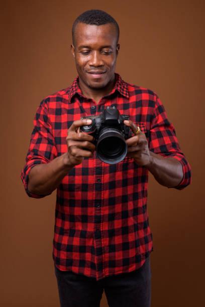 istock Studio shot of muscular African man with camera against colored background 855505554