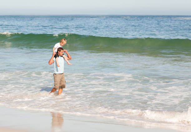 istock Father giving son a piggyback on the beach 855505630