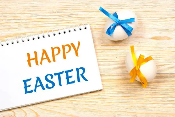 happy easter, yellow and blue colored message over rustic desk