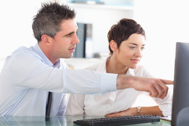 istock Man showing something to his coworker on a computer 855512700