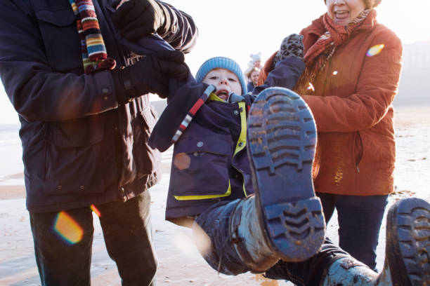 istock Grandparents Swing Their Grandson While Walking Along the Beach 855520436