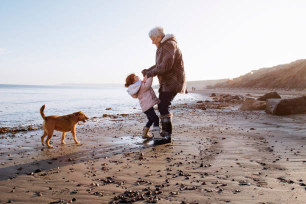 oma mit ihrer enkelin am strand - grandmother and grandaughter stock-fotos und bilder