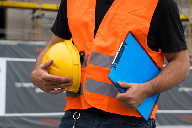 istock Cropped construction worker with orange safety vest holding a yellow helmet 855525520