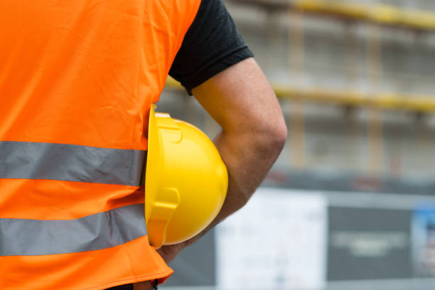 istock Cropped construction worker with orange safety vest holding a yellow helmet 855525564