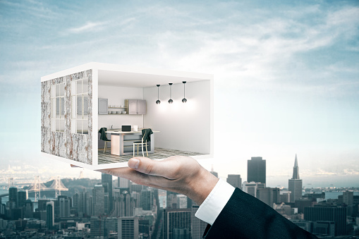 Hand holding abstract kitchen room on sky and city background. Residence owner concept. 3D Rendering