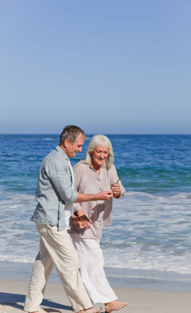 istock Elderly couple walking on the beach 855529420