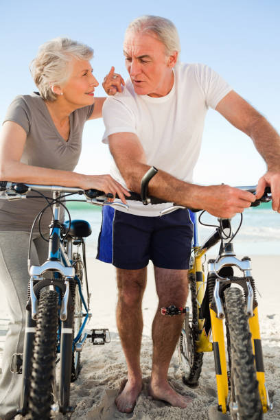 couple de retraités avec leurs vélos sur la plage - senior couple cycling beach bicycle photos et images de collection