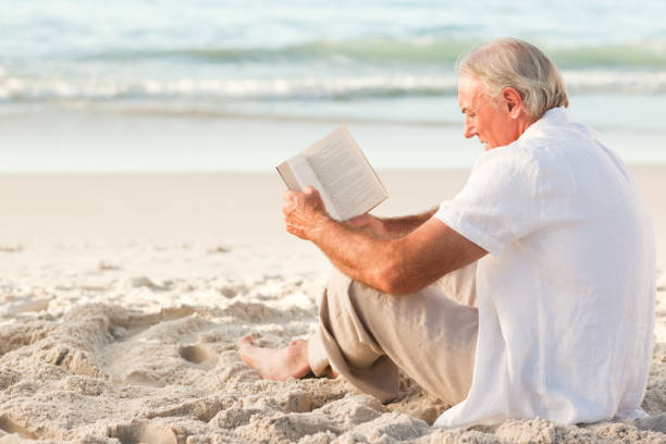 istock Man reading a book on the beach 855543008