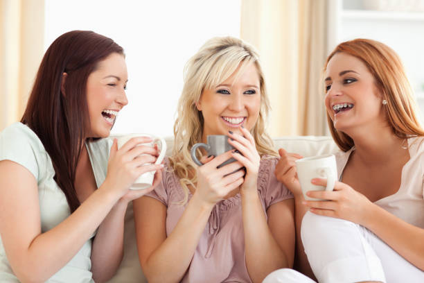 istock Joyful women sitting on a sofa with cups 855550284
