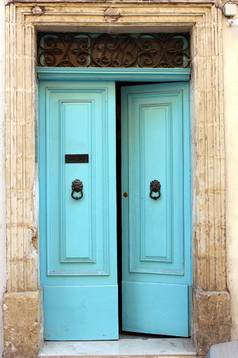 An old doorway in Malta, with blue turquoise paintwork and ironmongery, and limestone brickwork