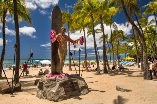 Duke Kahanamoku statue on Waikiki beach Hawaii Honolulu: Duke Kahanamoku statue in front of Kuhio Beach Park in Waikiki. Duke Paoa Kahinu Mokoe Hulikohola Kahanamoku (August 24, 1890 – January 22, 1968) was a Native Hawaiian competition swimmer who popularized the ancient Hawaiian sport of surfing. duke kahanamoku stock pictures, royalty-free photos & images