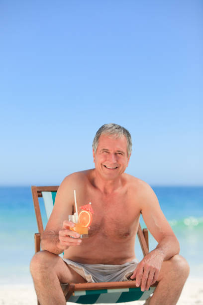 istock Senior man drinking a cocktail on the beach 855550928