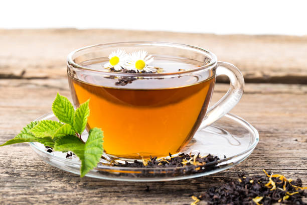 glass cup tea with camomile flower and mint leaf, on brown wooden palette - oregano freshness herb brown imagens e fotografias de stock