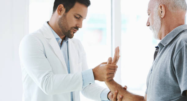 Wrist pain examination. Closeup side view of a mid 50's man having his wrist examined by a doctor. The patient has suffered a dislocation by physical injury. wrist stock pictures, royalty-free photos & images