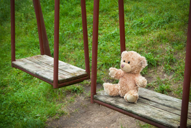 istock Teddy bear sitting on the swing. Loneliness concept 855573982