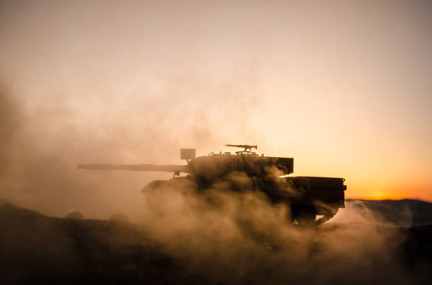 戦争の概念。戦争の霧空のシーンをかけて戦う軍のシルエットの背景、日没時曇りスカイライン以下世界大戦兵士のシルエット。攻撃シーン。ドイツのタンク内のアクション - fire power ストックフォトと画像