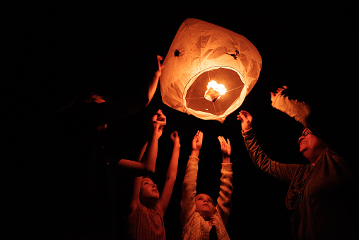 Group of friends launching a paper lantern at night in Quebec Canada. Family