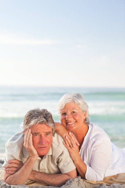 istock Elderly couple lying down on the beach 855581236