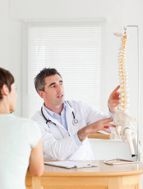 의사가 여성 환자는 척추의 일부를 보여주는 - doctor patient chiropractic adjustment communication 뉴스 사진 이미지