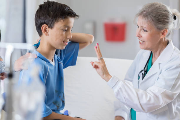 How many fingers am I holding up? Senior female emergency room doctor holds up two fingers to young injured soccer player. self mutilation pictures stock pictures, royalty-free photos & images