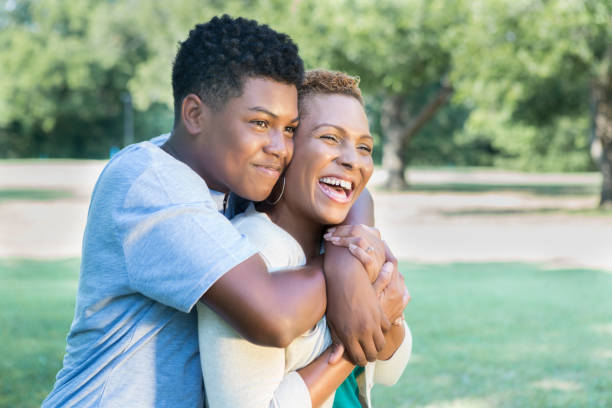 le fils adolescent aimant donne sa maman un câlin - teenager african descent laughing adolescence photos et images de collection