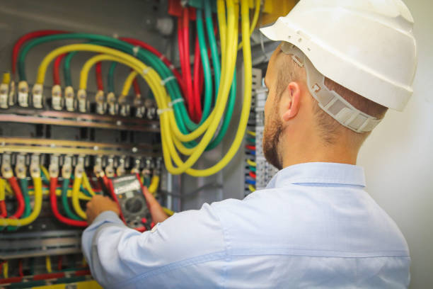 istock electrician engineer measures voltage of electrical power cables in cabinet. worker in white helmet with multimeter 855601072